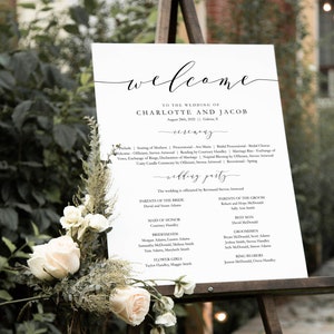 May include: A white wedding welcome sign with black calligraphy text. The sign lists the wedding date, location, and the names of the bride and groom. It also includes the names of the wedding party members, including the maid of honor, bridesmaids, groomsmen, and ring bearers.
