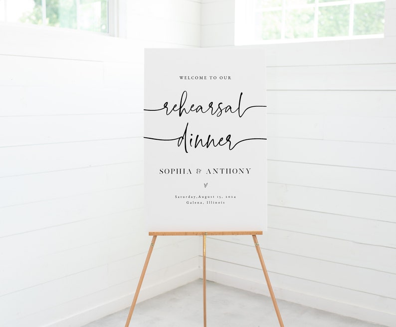 May include: White sign with black text announcing a rehearsal dinner for Sophia and Anthony. The event is scheduled for Saturday, August 11th in Galena, Illinois.