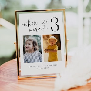 May include: A gold framed photo display with the text "when we were 3" and two photos of children. The names "Courtney and Anthony" and the date "07.21.202X" are printed below the photos. The display is on a wooden surface.