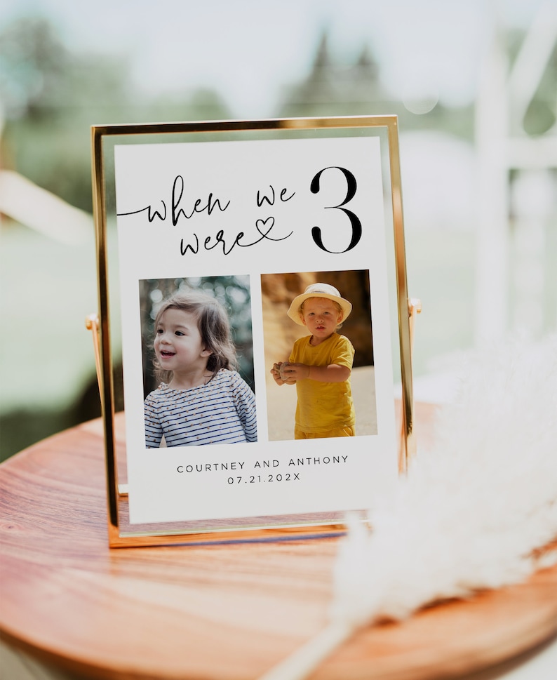 May include: A gold framed photo display with the text "when we were 3" and two photos of children. The names "Courtney and Anthony" and the date "07.21.202X" are printed below the photos. The display is on a wooden surface.