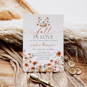 Puede incluir: Una invitación a una despedida de soltera con temática otoñal con una ilustración de acuarela de calabazas y flores. La invitación dice "Fall in Love" e incluye el nombre de la novia, la fecha, la hora, el lugar, la información de RSVP y los detalles del registro.