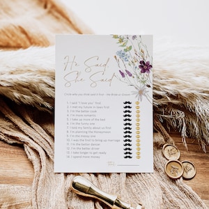 May include: A printable wedding game card with a floral design. The card has the text "He Said, She Said" and asks guests to circle who they think said each statement first, the bride or the groom. The card includes 14 statements about the couple's relationship.