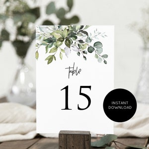 May include: White table number card with green watercolor foliage and the text "Table 15" in black.