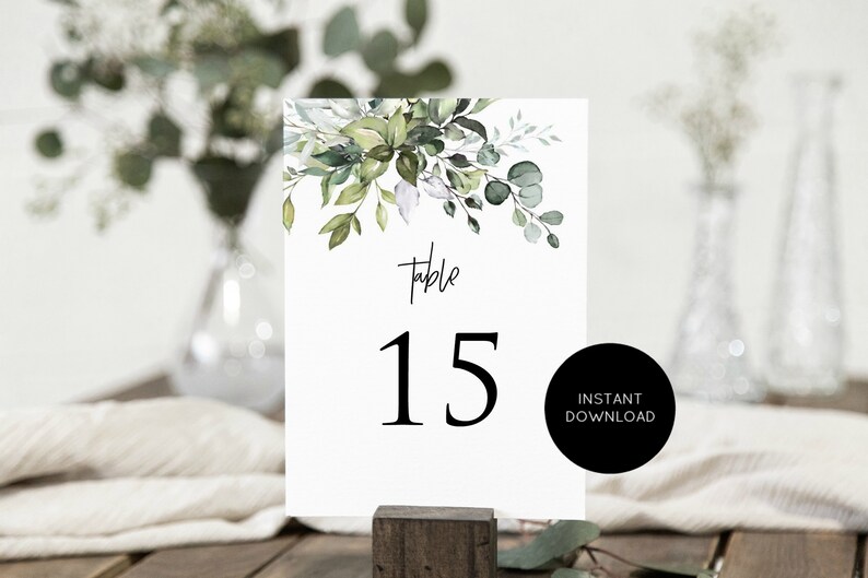 May include: White table number card with green watercolor foliage and the text "Table 15" in black.