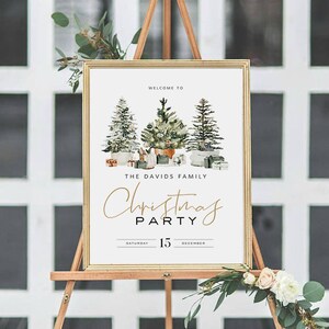 May include: A white sign with gold trim and a welcome to the Davids family Christmas party sign. The sign features a watercolor illustration of three Christmas trees with presents underneath. The text reads "Welcome to The Davids Family Christmas Party Saturday 15 December".