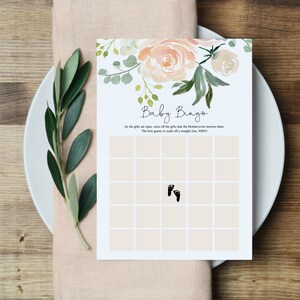 May include: A printable baby bingo card with a floral design. The card has a grid of squares with a footprint in one of the squares. The text on the card reads "Baby Bingo" and "As the gifts are open, cross off the gifts that the Mother-to-be receives them. The first guest to mark off a straight line, WINS!"