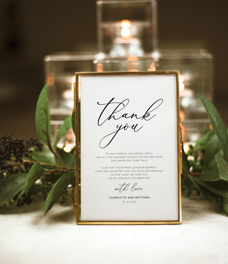 Puede incluir: Una tarjeta blanca con borde dorado en un marco dorado con el texto "Gracias" en letra elegante. La tarjeta expresa gratitud a los invitados por su apoyo y amor en una boda. La tarjeta est&aacute; firmada "Charlotte y Matthew" con la fecha "10.20.2022".