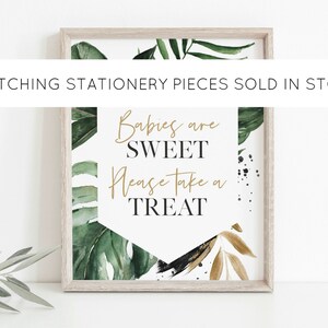 May include: A framed print with a tropical leaf design and the text "Babies are sweet, please take a treat".