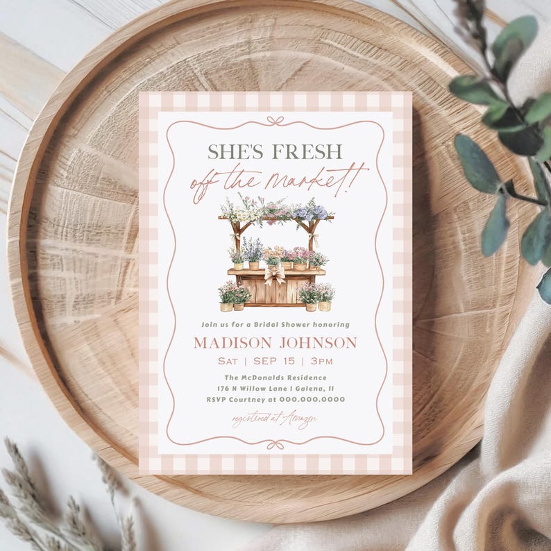 May include: A bridal shower invitation with a watercolor illustration of a flower stand. The invitation features the text "SHE'S FRESH off the market!" and details for Madison Johnson's shower, set against a pink gingham background.