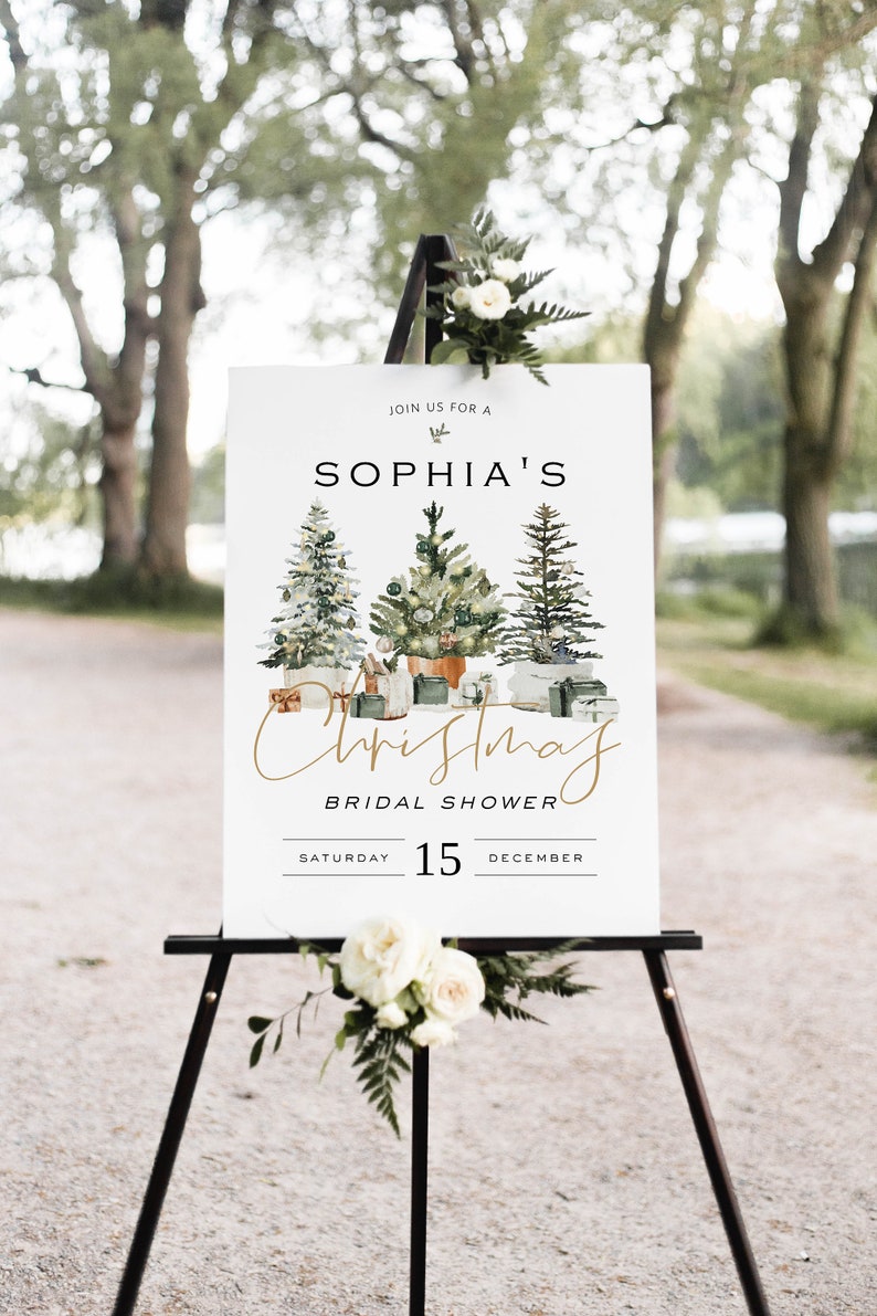 Puede incluir: Un cartel blanco con texto dorado anunciando una despedida de soltera navide&ntilde;a para Sophia el s&aacute;bado 15 de diciembre. El cartel presenta una ilustraci&oacute;n de acuarela de tres &aacute;rboles de Navidad decorados.