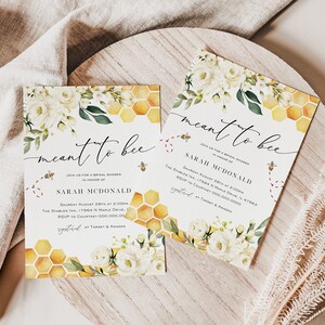 May include: A bridal shower invitation with a bee and honeycomb theme. The invitation is white with yellow and gold honeycomb patterns and white flowers. The text on the invitation reads "meant to bee" and "Join us for a bridal shower in honor of Sarah McDonald".
