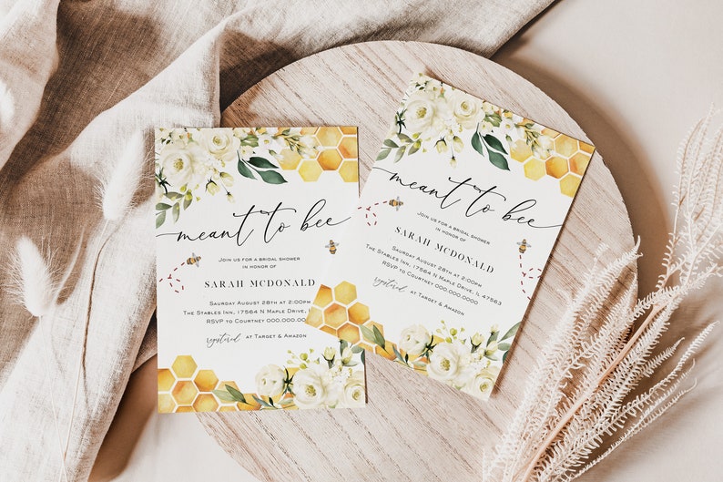 May include: A bridal shower invitation with a bee and honeycomb theme. The invitation is white with yellow and gold honeycomb patterns and white flowers. The text on the invitation reads "meant to bee" and "Join us for a bridal shower in honor of Sarah McDonald".