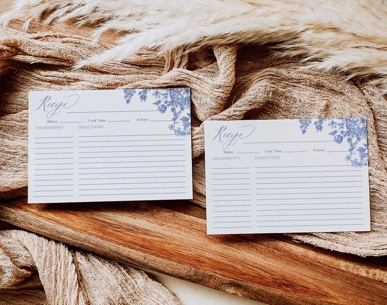 May include: Two blank recipe cards with a blue floral design. The cards have spaces for the recipe name, ingredients, directions, cook time, and servings.