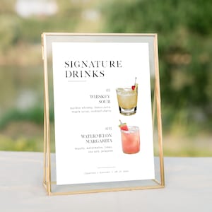 May include: A white sign with black text that reads "SIGNATURE DRINKS" and lists two cocktails: "Whiskey Sour" and "Watermelon Margarita".  Each cocktail is illustrated with a drawing of a glass with a cherry and a slice of watermelon.