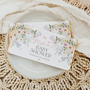 May include: A white chocolate bar with a floral design and the text "Meghan's Baby Shower thank you for coming!" in pink and black lettering.