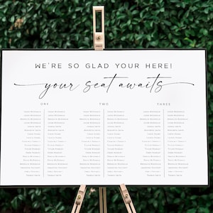 Könnte beinhalten: Ein weißer Hochzeitsplatzplan mit schwarzem Text. Der Plan ist mit "We're so glad you're here! Your seat awaits." betitelt und listet die Namen der Gäste unter den Überschriften "One", "Two" und "Three" auf.