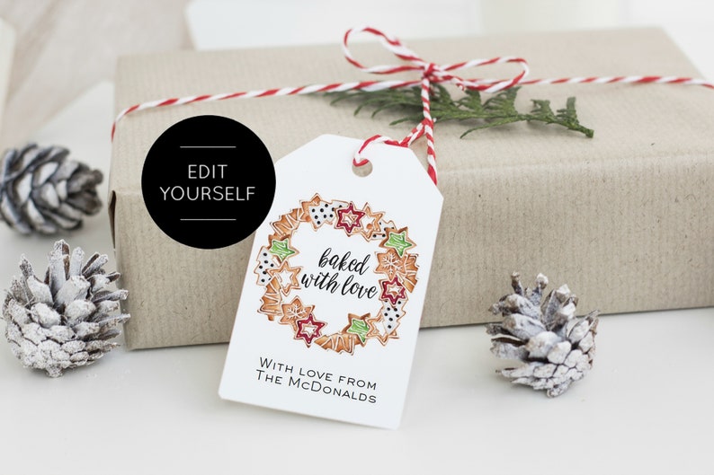 May include: White gift tag with a red and white string tied around it. The tag has a drawing of a wreath made of gingerbread cookies with the text "baked with love". The text "With love from The McDonalds" is printed below the wreath.