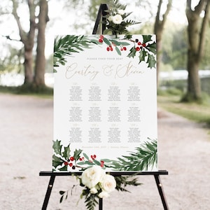 May include: A wedding seating chart with a winter theme. The chart is printed on white paper with a green and red watercolor design of holly and berries. The text reads "Please find your seat" and "Courtney & Steven" in gold lettering. The date and location are listed at the bottom: "December 14th, 2022 | Galena, Illinois".