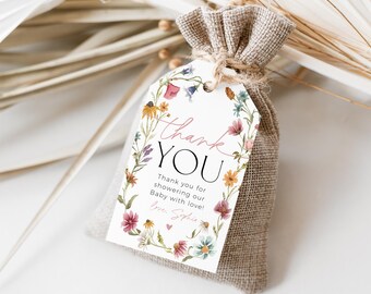 May include: A white thank you tag with a floral wreath border and the text "Thank you for showering our Baby with love! Love, Sophie" in pink and black lettering. The tag is attached to a small burlap bag.