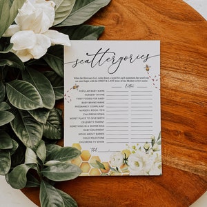 May include: A printable baby shower game called "Scattergories" with a honeycomb pattern and floral design. Players must write down a word for each statement that begins with the first and last letter of the mother-to-be's name.