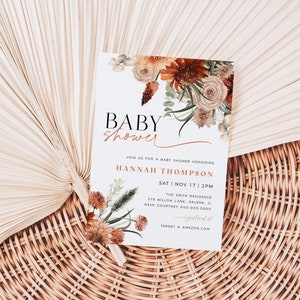 May include: A white baby shower invitation with a floral design in shades of orange, brown, and white. The text reads "Baby Shower" in a black and white font, followed by "Join us for a baby shower honoring Hannah Thompson" in a brown font. The date and time of the shower are listed as "Sat | Nov 17 | 2PM". The location is listed as "The Smith Residence, 276 Willow Lane, Galena, IL". The RSVP information is listed as "RSVP Courtney 000-000-0000". The bottom of the invitation reads "Target & Amazon.com".