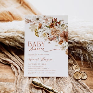 May include: A baby shower invitation with a floral design in shades of brown, beige, and white. The text reads "Baby Shower" and "Hannah Thompson". The date and time of the shower are listed as "Sat Nov 17 | 2PM". The location is "The Smith Residence, 276 Willow Lane, Galena, IL". The RSVP information is "Kindly RSVP Courtney 000.000.0000". The invitation also includes the text "Registered at Target & Amazon.com".