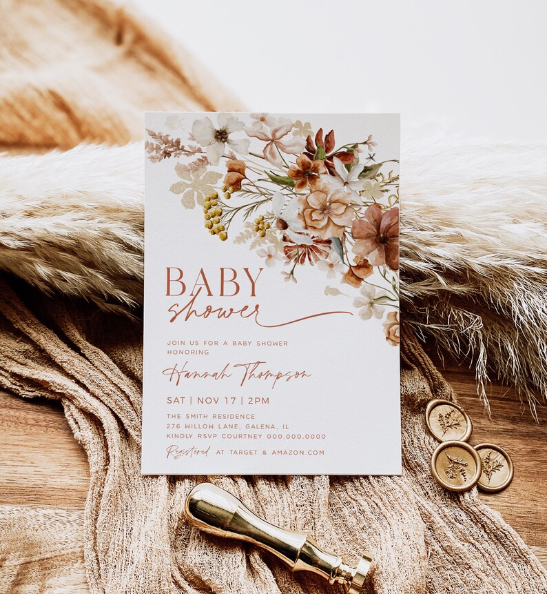 May include: A baby shower invitation with a floral design in shades of brown, beige, and white. The text reads "Baby Shower" and "Hannah Thompson". The date and time of the shower are listed as "Sat Nov 17 | 2PM". The location is "The Smith Residence, 276 Willow Lane, Galena, IL". The RSVP information is "Kindly RSVP Courtney 000.000.0000". The invitation also includes the text "Registered at Target & Amazon.com".