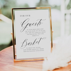 May include: A white sign with black text in a gold frame. The sign reads "For Our Guests" and includes instructions for guests to use a basket to help them along. The sign is on a wooden surface.