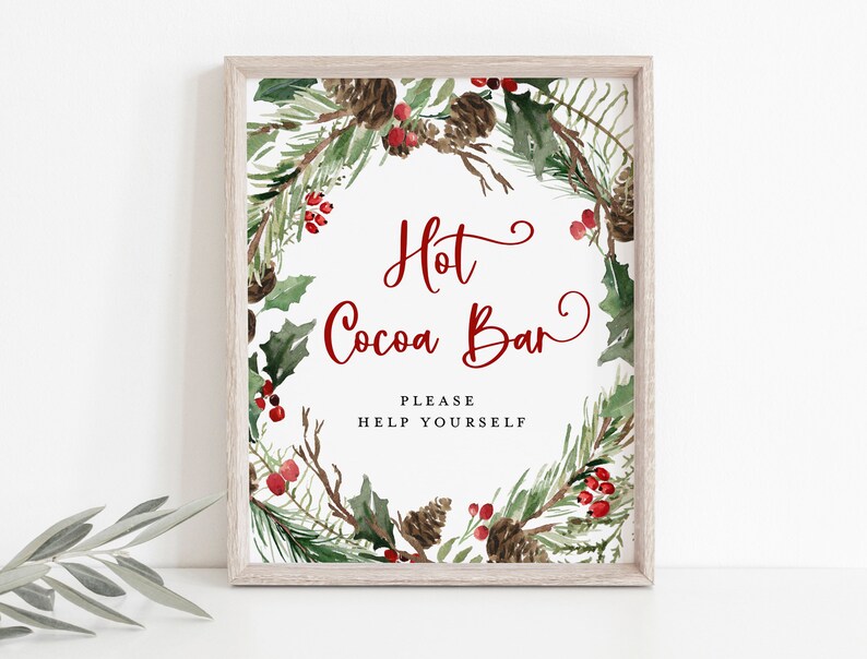 May include: A printable sign with a watercolor wreath of pine branches, holly, and red berries. The sign says "Hot Cocoa Bar" with the text "Please Help Yourself" below.