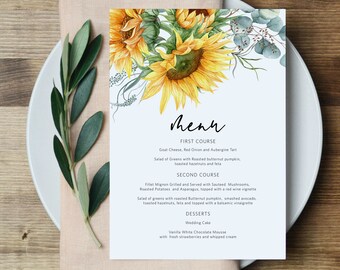 May include: A wedding menu card with a watercolor illustration of sunflowers and eucalyptus leaves. The menu includes a first course of goat cheese, red onion, and aubergine tart, a second course of filet mignon with sauteed mushrooms, roasted potatoes, and asparagus, and desserts of wedding cake and vanilla white chocolate mousse.