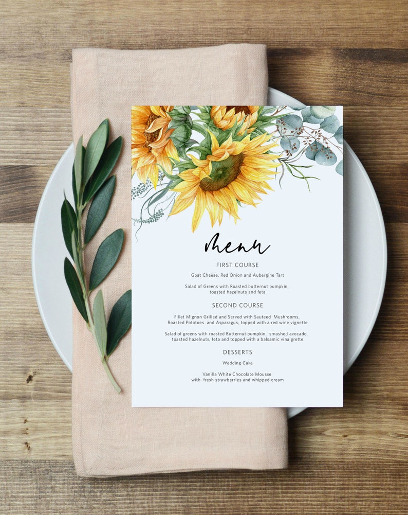 K&ouml;nnte beinhalten: Eine Hochzeitsmen&uuml;karte mit einer Aquarell-Illustration von Sonnenblumen und Eukalyptusbl&auml;ttern. Das Men&uuml; umfasst eine Vorspeise mit Ziegenk&auml;se, roter Zwiebel und Auberginentarte, ein Hauptgericht mit Filet Mignon mit sautierten Pilzen, Bratkartoffeln und Spargel sowie Desserts mit Hochzeitstorte und Vanille-Wei&szlig;schokoladenmousse.