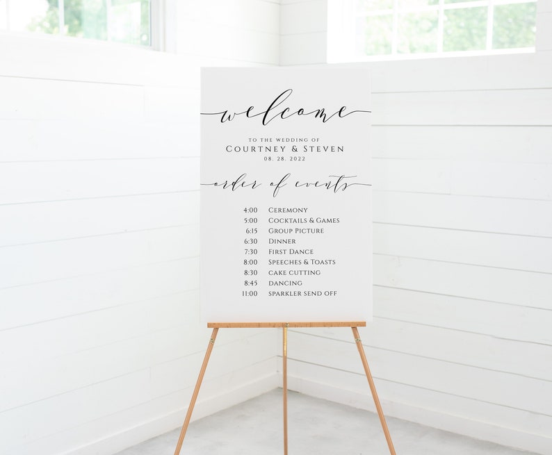 May include: White wedding welcome sign with black calligraphy text. The sign lists the order of events for the wedding of Courtney and Steven on August 28, 2022.