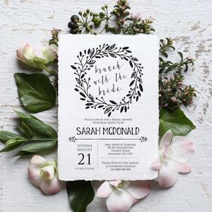 May include: A white invitation with black text and a floral wreath design. The text reads "branch with the bride" and includes details for a bridal shower for Sarah McDonald. The event is scheduled for Saturday, August 21st at two o'clock at Miss Marples Tearoom, 382 Mt Dandenong Tourist Road, Sassafras VIC 3787. RSVP by August 12th to Courtney Handley at 0000 000 000.