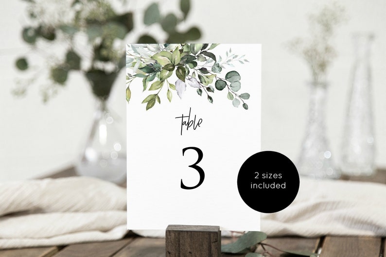 May include: A white table number card with a watercolor illustration of green leaves and the text "Table 3" in black.