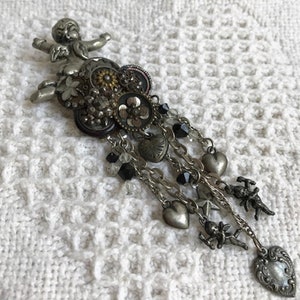 May include: A silver charm bracelet with a cherub, hearts, and other charms. The bracelet is made of metal and has a chain link design.