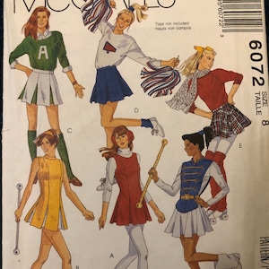 Könnte beinhalten: Ein Schnittmuster für eine Marschbanduniform. Das Muster umfasst fünf verschiedene Rockmodelle, darunter ein weißer Rock mit goldenen Verzierungen, ein roter Rock, ein gelber Rock, ein grüner Rock mit weißen Verzierungen und ein blauer Rock mit goldenen Verzierungen. Das Muster umfasst auch ein weißes Hemd mit einem roten Logo, ein rotes Hemd mit einem weißen Logo und ein grünes Hemd mit einem weißen Logo. Das Muster ist für Größe 8.