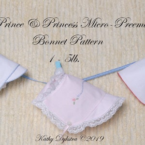 May include: Three baby bonnets hanging on a clothesline. The bonnets are white with embroidered designs. The bonnets are labeled "Prince & Princess Micro-Preemie Bonnet Pattern 1-5lb."