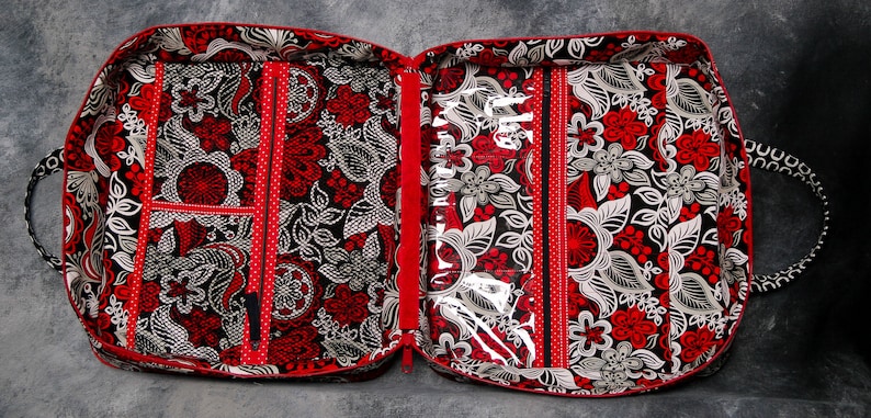 May include: A red and black zippered travel case with multiple compartments and a clear plastic window. The case has a floral pattern and is lined with red fabric.
