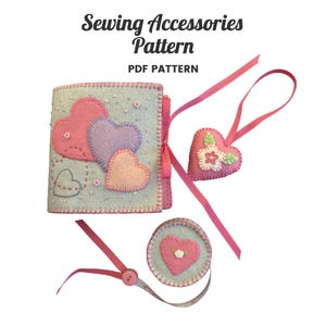May include: A sewing accessories pattern PDF pattern featuring a light blue felt needle book with pink, purple, and peach heart appliqués, a heart-shaped felt ornament with a flower, and a circular felt tape measure case with a pink heart.