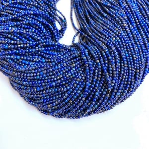 May include: A strand of deep blue lapis lazuli beads, each bead is round and smooth. The beads are arranged in a circular pattern, creating a beautiful and intricate design.