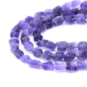 May include: A strand of purple amethyst gemstone beads. The beads are rough and irregular in shape, giving them a natural, raw look.