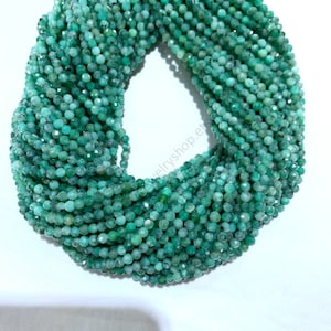 May include: A strand of green emerald faceted beads, approximately 4mm in size. The beads are strung on a clear thread and are ready for jewelry making.