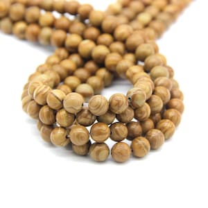 May include: A strand of brown and white striped round beads. The beads are made of natural stone and have a smooth, polished finish.