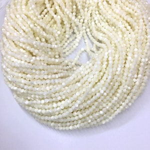 Peut inclure: Une grande collection de petites perles facettées blanc cassé. Les perles sont enfilées ensemble, créant une surface dense et texturée. Les perles ont un éclat subtil, reflétant la lumière. L'aspect général est d'une couleur douce et crémeuse.