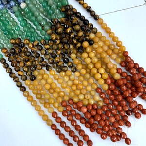 May include: A strand of faceted gemstone beads in various colors, including green, brown, yellow, and red. The beads are arranged in rows, with the green beads at the top and the red beads at the bottom.