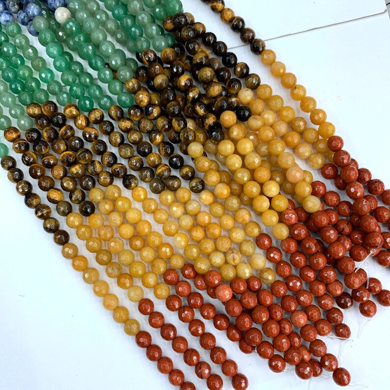 May include: A strand of faceted gemstone beads in various colors, including green, brown, yellow, and red. The beads are arranged in rows, with the green beads at the top and the red beads at the bottom.