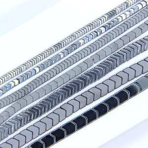 May include: A collection of gray and black arrow-shaped ceramic tiles arranged in rows. The tiles are glossy and have a reflective surface.