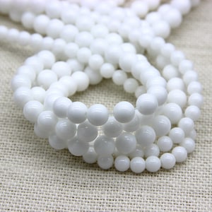 May include: A strand of white round beads, made of natural stone, for jewellery making.