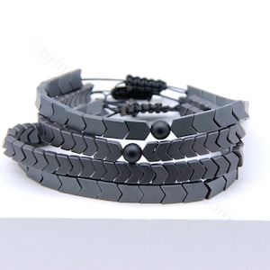 May include: A black bracelet made of arrow-shaped beads with two black round beads in the centre.