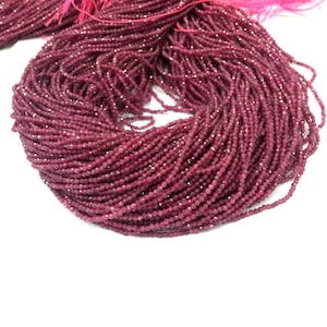 May include: A strand of deep red ruby beads, each bead is faceted and measures approximately 2mm in diameter. The beads are strung on a thin thread and are ready for jewelry making.